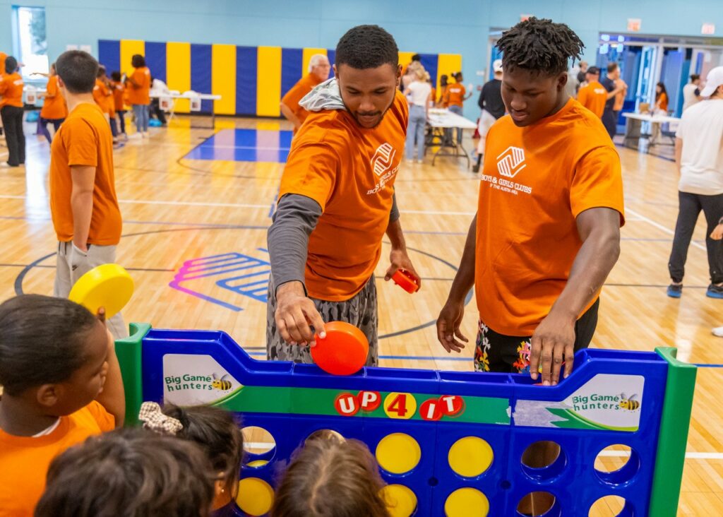 Boys & Girls Club volunteers play a game with a group of children in a gym